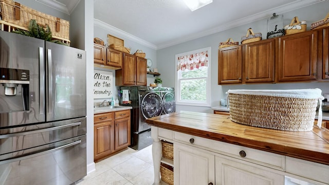 kitchen with stainless steel refrigerator with ice dispenser, butcher block counters, light tile patterned floors, ornamental molding, and independent washer and dryer