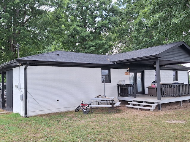 back of property with a deck and a lawn