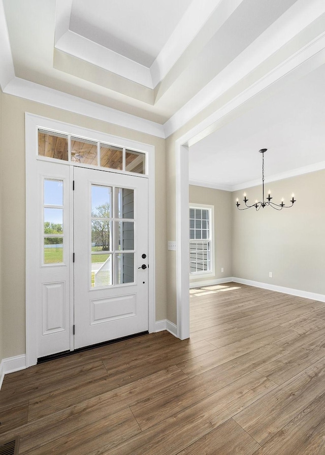 foyer entrance featuring a healthy amount of sunlight, dark hardwood / wood-style floors, an inviting chandelier, and a tray ceiling