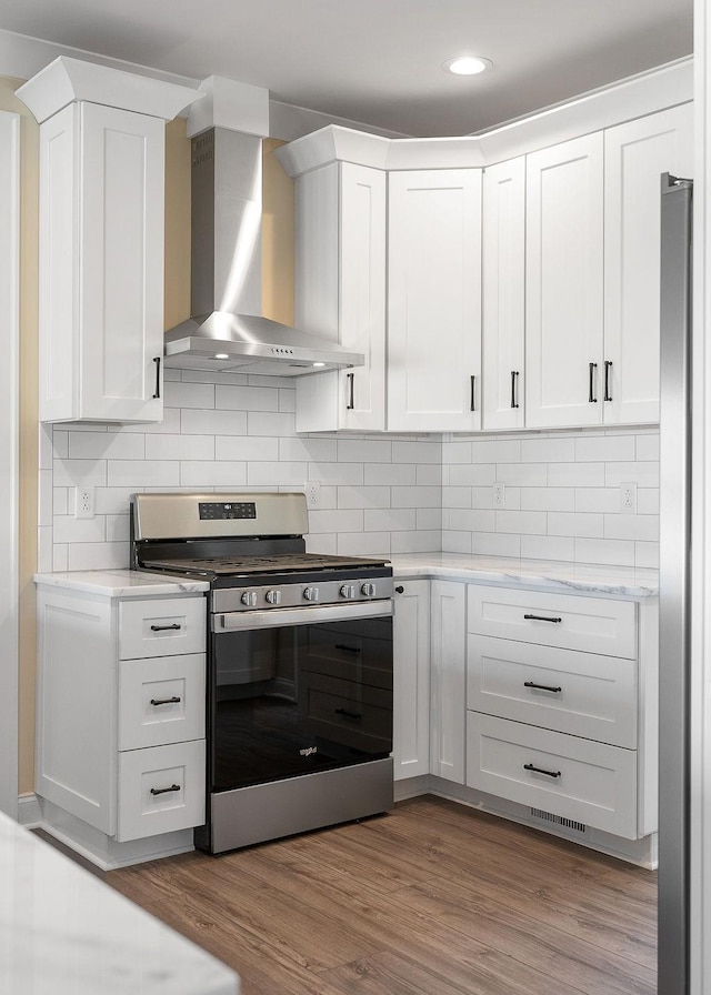 kitchen featuring white cabinetry, wall chimney range hood, and appliances with stainless steel finishes