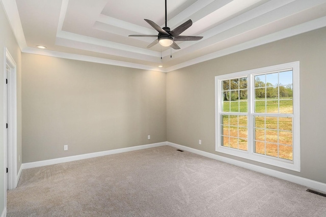 carpeted spare room featuring a raised ceiling and ceiling fan