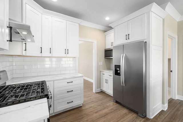 kitchen featuring dark wood-type flooring, extractor fan, white cabinetry, appliances with stainless steel finishes, and light stone countertops