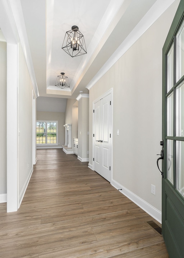 entryway with hardwood / wood-style flooring, a raised ceiling, and a notable chandelier