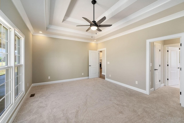 empty room featuring light carpet, a raised ceiling, and ceiling fan