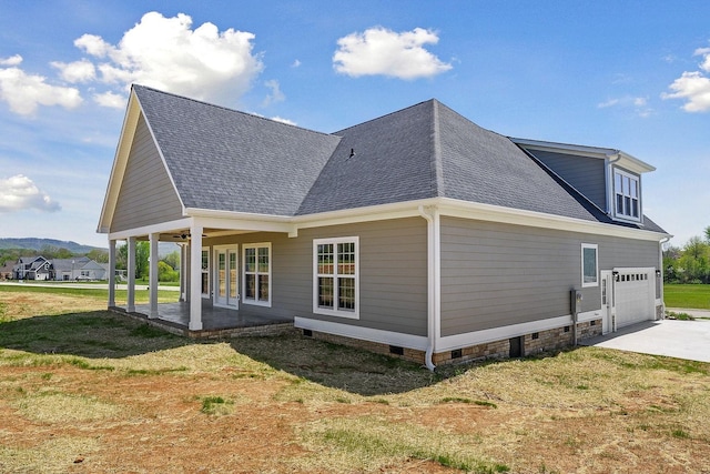 rear view of property featuring a garage, a yard, and covered porch