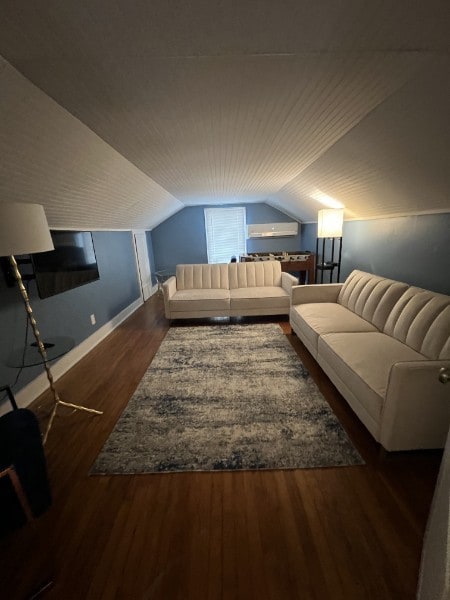 additional living space featuring vaulted ceiling and dark wood-type flooring