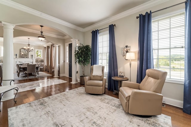 sitting room with decorative columns, crown molding, hardwood / wood-style flooring, and a chandelier