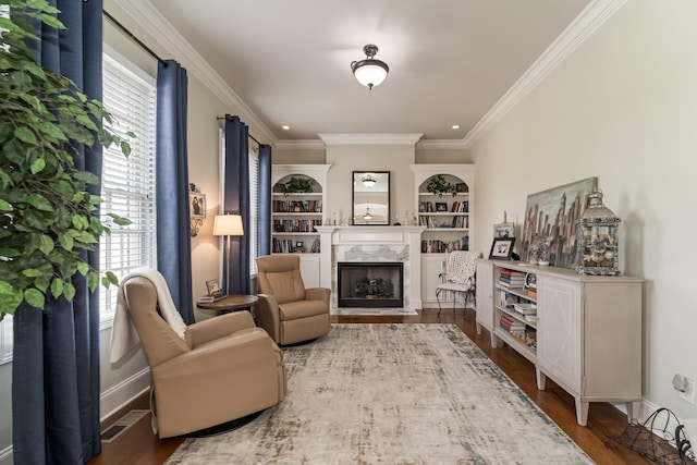 living area featuring hardwood / wood-style flooring, ornamental molding, a premium fireplace, and built in shelves