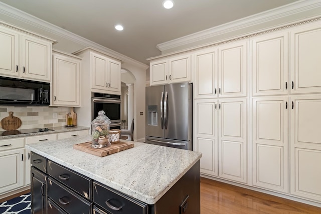 kitchen with crown molding, tasteful backsplash, a kitchen island, hardwood / wood-style floors, and black appliances