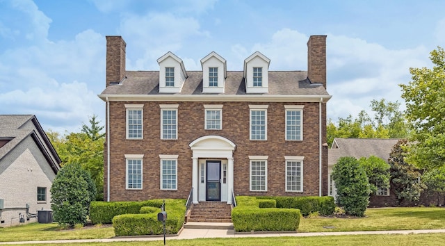 colonial inspired home featuring central AC unit and a front lawn