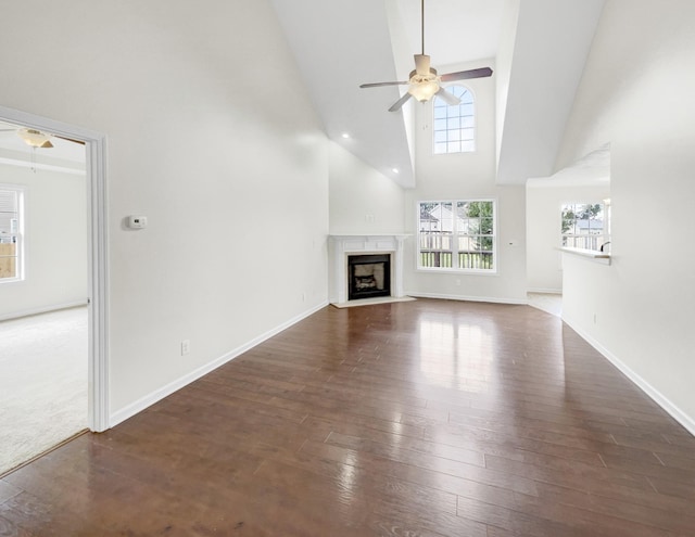 unfurnished living room with dark hardwood / wood-style floors, ceiling fan, a fireplace, and high vaulted ceiling