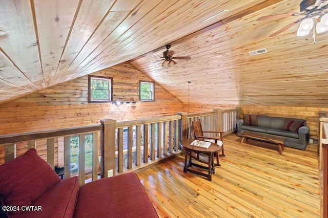 living area with a healthy amount of sunlight, wooden walls, light hardwood / wood-style flooring, and wooden ceiling