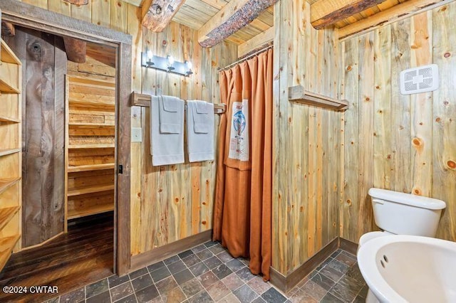 bathroom with wood ceiling, wooden walls, beam ceiling, and toilet