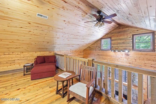 living area with wood walls, lofted ceiling, light hardwood / wood-style flooring, and wooden ceiling