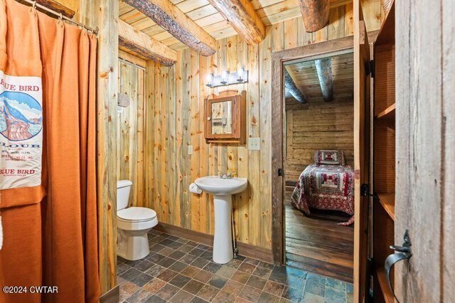 bathroom featuring wooden ceiling, toilet, beamed ceiling, and wood walls