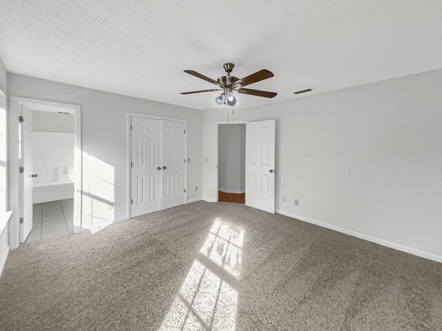 unfurnished bedroom featuring ceiling fan, connected bathroom, light colored carpet, and a textured ceiling