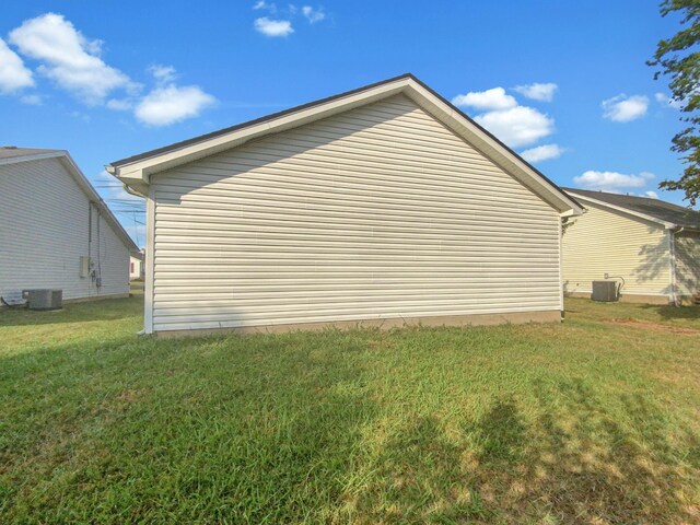 view of side of property featuring a lawn and central AC