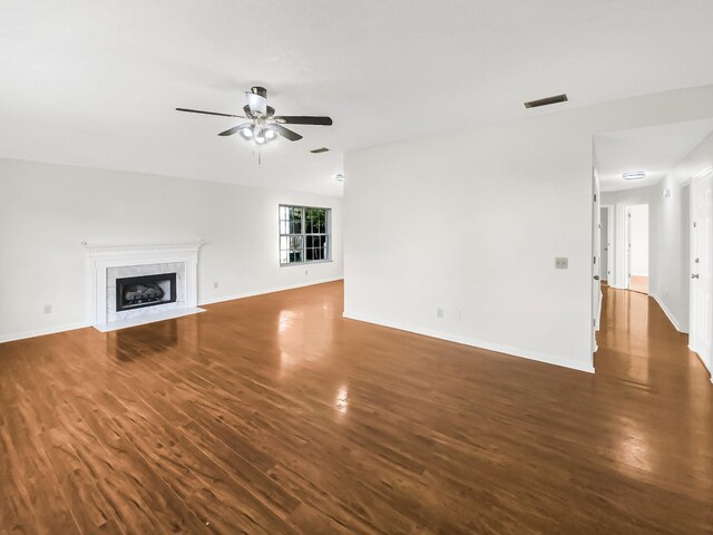 unfurnished living room featuring dark hardwood / wood-style flooring, a tile fireplace, and ceiling fan