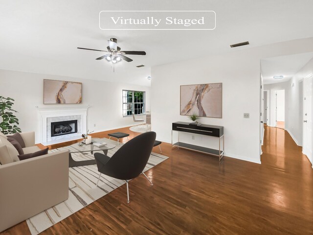 living room featuring a tiled fireplace, ceiling fan, and hardwood / wood-style floors