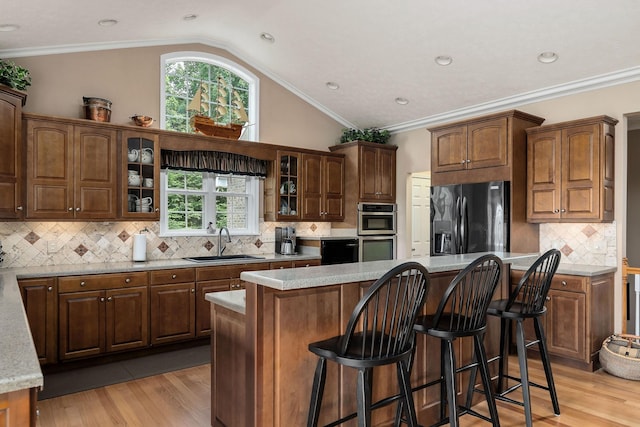 kitchen with sink, a breakfast bar, fridge with ice dispenser, a kitchen island, and vaulted ceiling