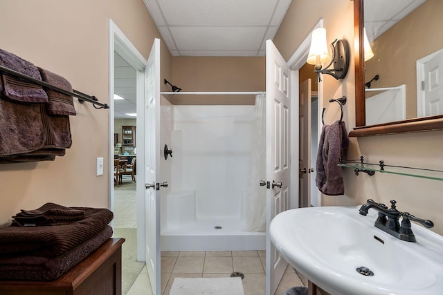 bathroom with a drop ceiling, sink, tile patterned floors, and walk in shower