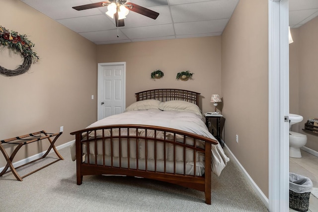 carpeted bedroom featuring ceiling fan, a drop ceiling, and ensuite bath