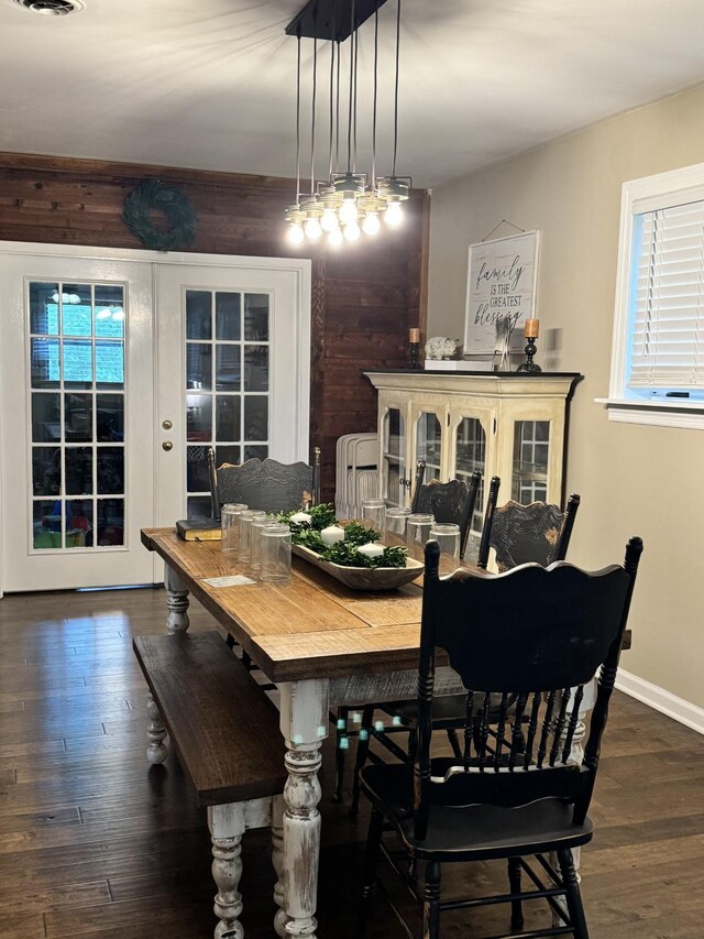 dining room featuring wood walls, dark hardwood / wood-style flooring, and plenty of natural light