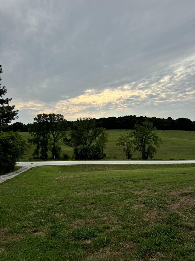 yard at dusk featuring a rural view