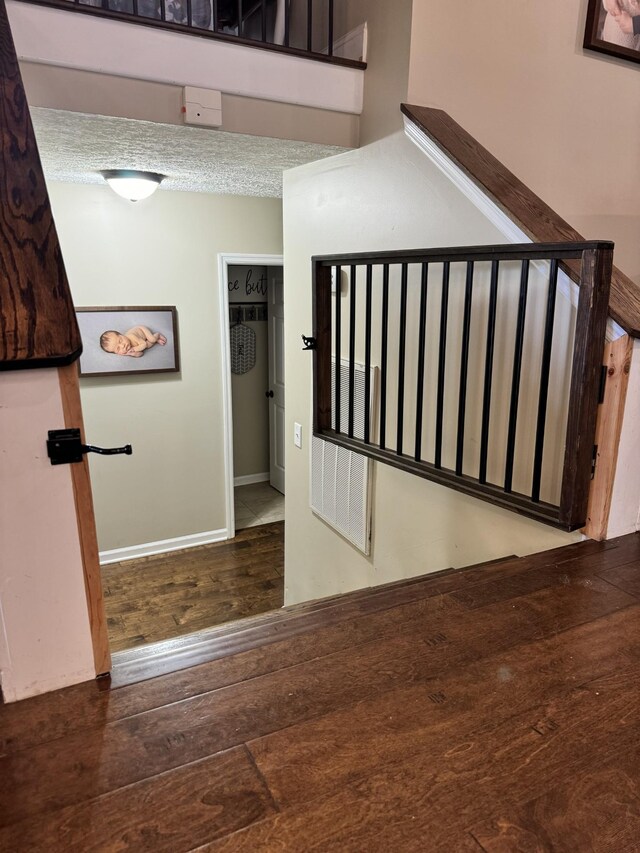 stairway with a textured ceiling and hardwood / wood-style floors