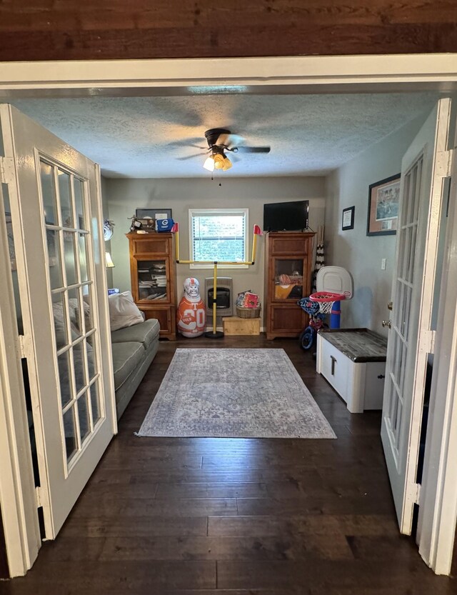 living room featuring dark hardwood / wood-style flooring, a textured ceiling, ceiling fan, and french doors