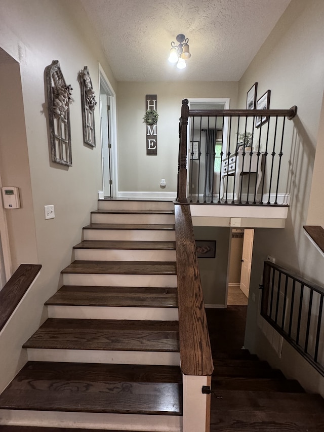 stairway featuring a textured ceiling and dark hardwood / wood-style floors