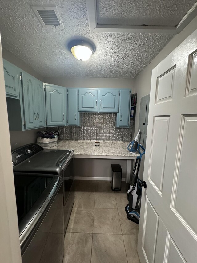 laundry room with washer and clothes dryer, a textured ceiling, cabinets, and light tile patterned floors