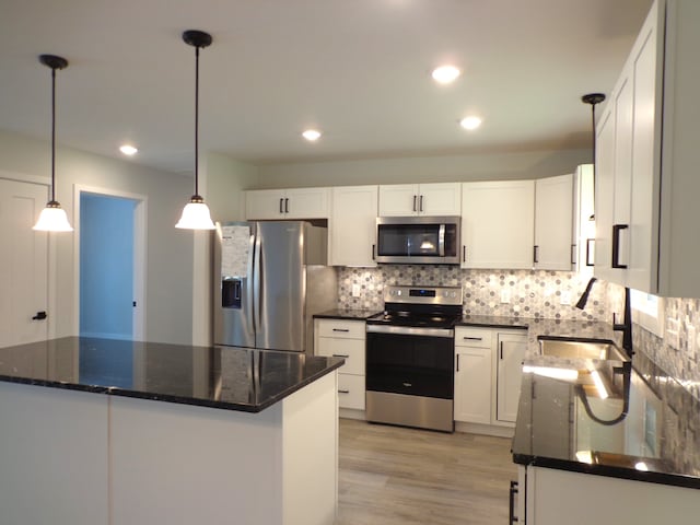 kitchen with hanging light fixtures, light hardwood / wood-style floors, stainless steel appliances, and white cabinets