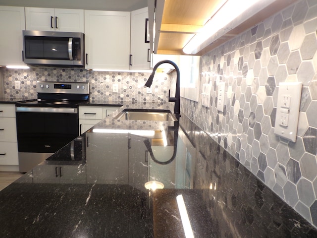 kitchen featuring dark stone counters, sink, white cabinetry, decorative backsplash, and appliances with stainless steel finishes