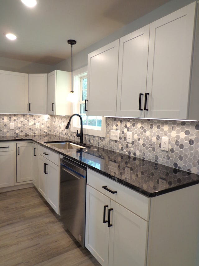 kitchen featuring stainless steel dishwasher, sink, pendant lighting, and white cabinets