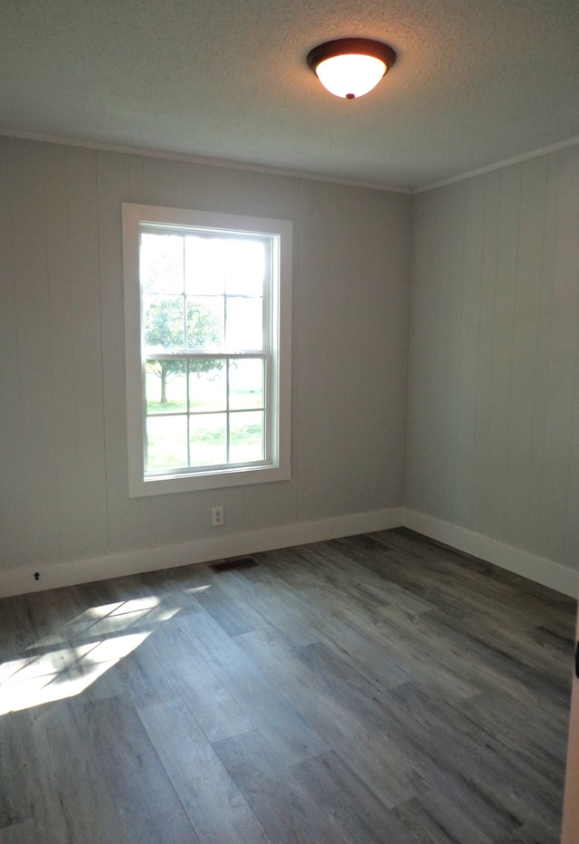 empty room featuring ornamental molding, a textured ceiling, and dark hardwood / wood-style flooring