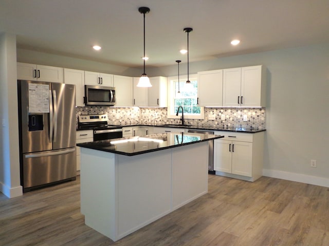 kitchen with a center island, dark wood-type flooring, white cabinets, stainless steel appliances, and decorative light fixtures