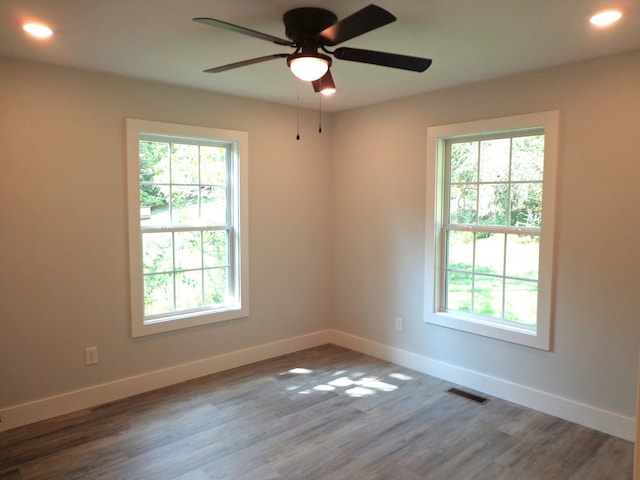 unfurnished room featuring ceiling fan, hardwood / wood-style flooring, and a healthy amount of sunlight