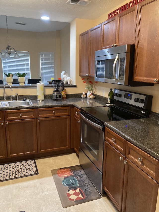 kitchen with light tile patterned floors, stainless steel appliances, pendant lighting, sink, and kitchen peninsula