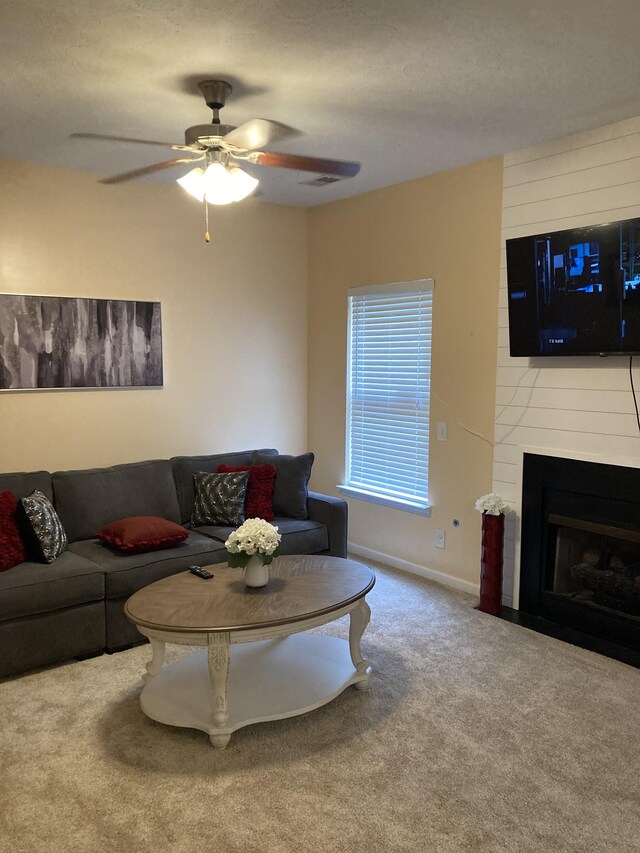 carpeted living room featuring a fireplace and ceiling fan