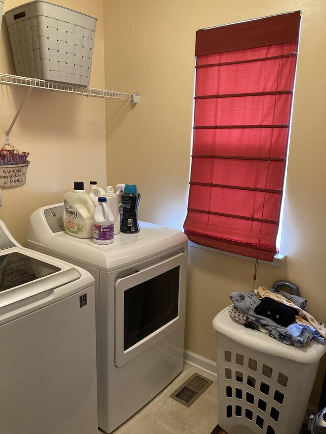 clothes washing area with separate washer and dryer and tile patterned floors