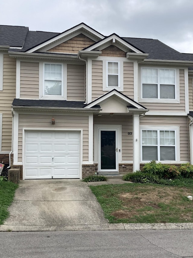 townhome / multi-family property with concrete driveway, roof with shingles, and an attached garage