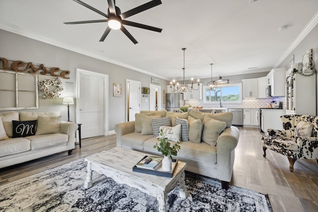 living room featuring crown molding, ceiling fan with notable chandelier, wood-type flooring, and sink