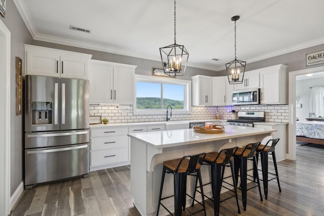 kitchen featuring white cabinetry, a center island, appliances with stainless steel finishes, dark hardwood / wood-style floors, and pendant lighting