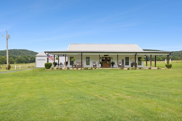 rear view of property featuring a mountain view, a garage, a lawn, and covered porch