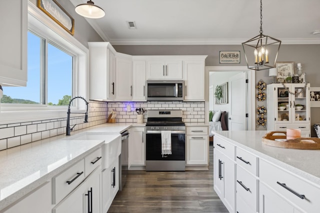 kitchen with pendant lighting, appliances with stainless steel finishes, backsplash, light stone counters, and white cabinets