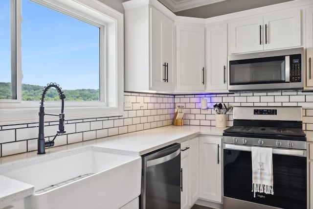 kitchen with appliances with stainless steel finishes, white cabinetry, sink, backsplash, and light stone countertops