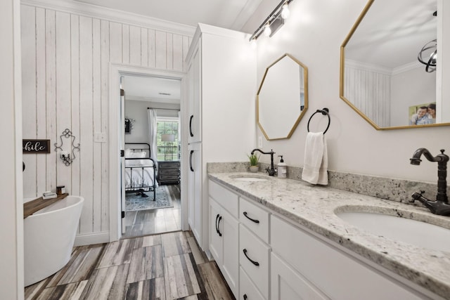 bathroom with vanity, a washtub, crown molding, and wood walls