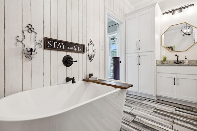 interior space with a tub to relax in, vanity, and ornamental molding