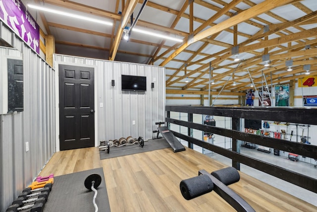 workout area featuring wood-type flooring, wooden walls, and vaulted ceiling